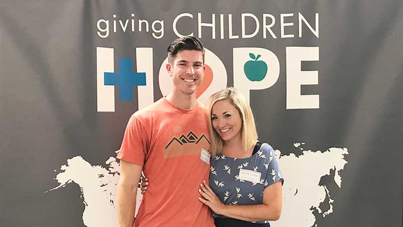 Case and his wife in front of sign that says, 'giving Children Hope'